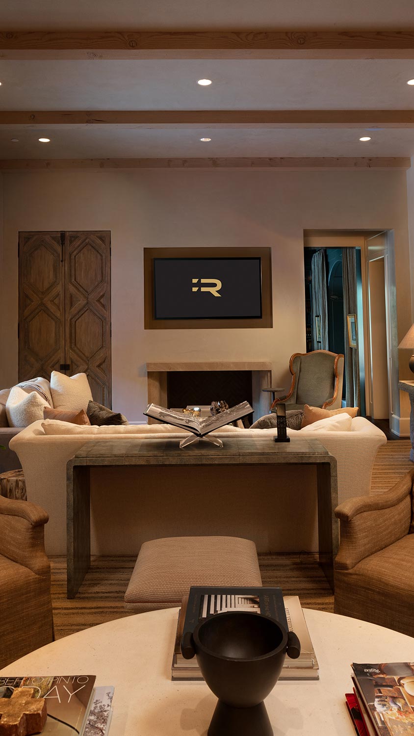 Cozy living room with beige furniture, wood accents, and a wall-mounted TV above a fireplace