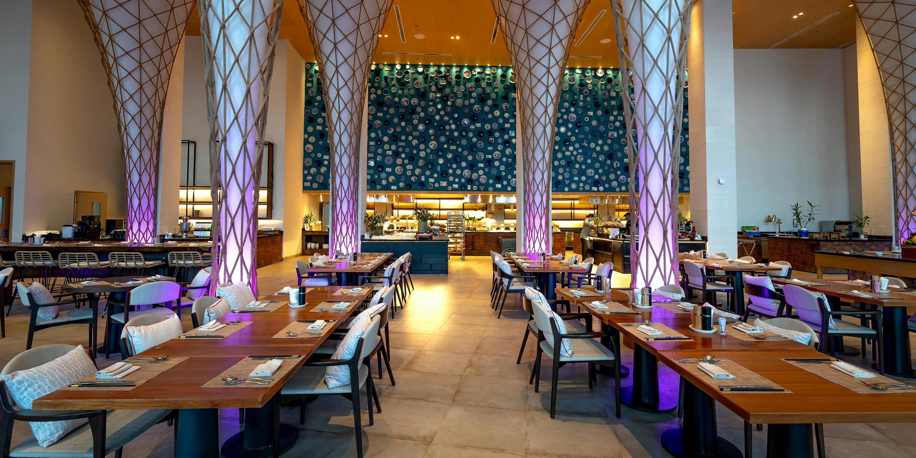 Upscale restaurant with wooden tables, decorative columns, and open kitchen