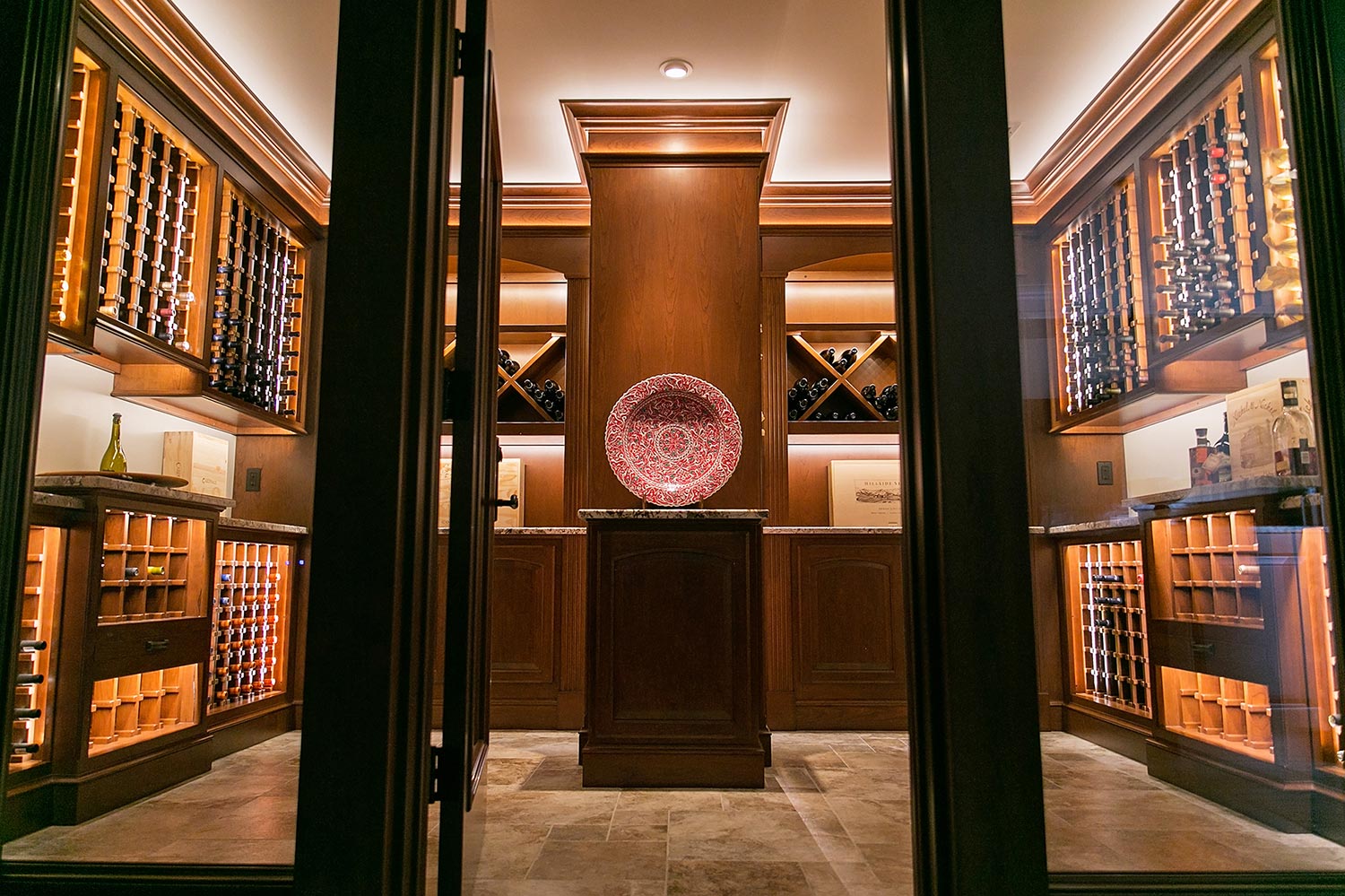 A wine cellar featuring illuminated wooden racks and a decorative centerpiece.