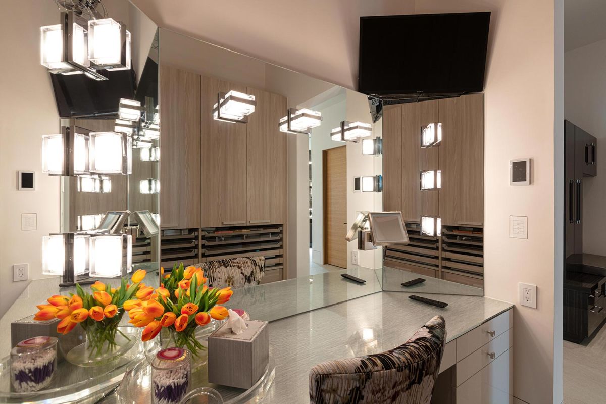 Vanity area with mirror lighting, mounted TV, and fresh tulips