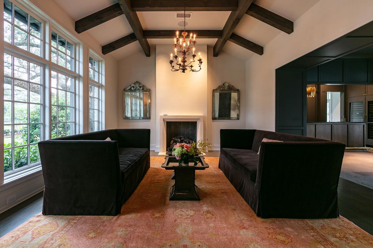 Sophisticated living room with twin black sofas, chandelier, and fireplace