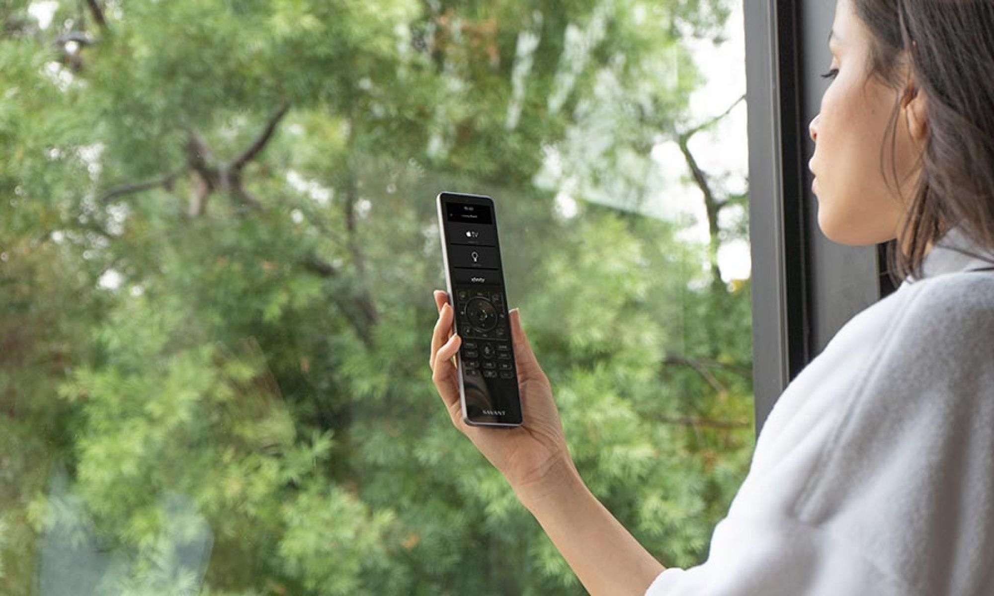 Woman holding a smart remote near a window