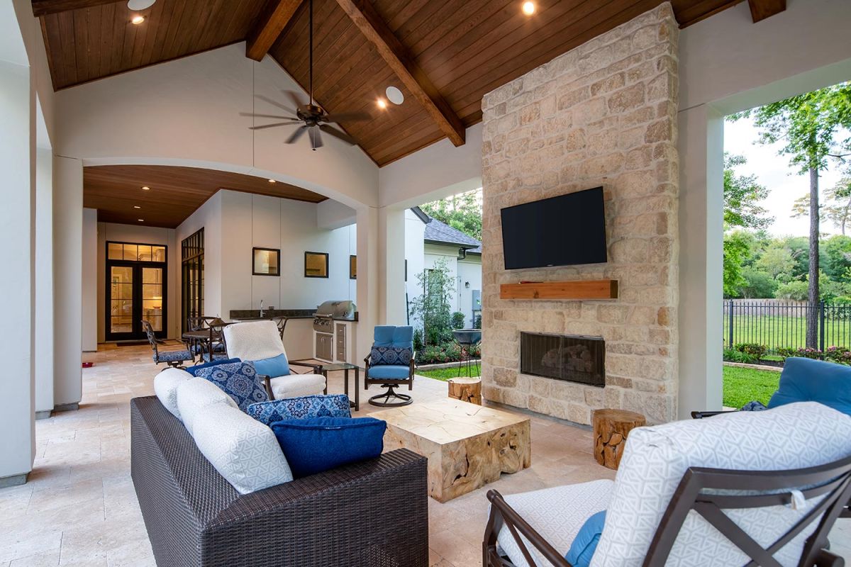 Covered patio with stone fireplace, TV, and outdoor seating