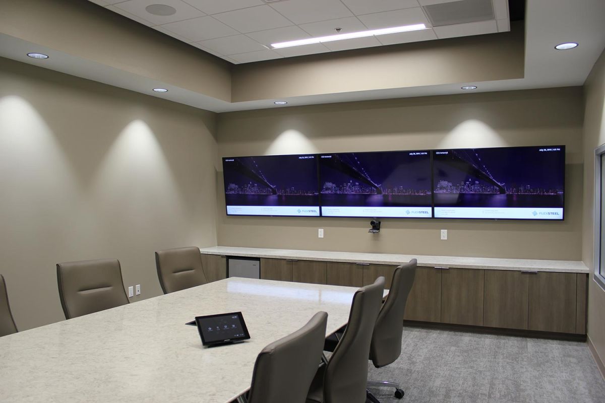 Meeting room with three large screens and video conferencing camera