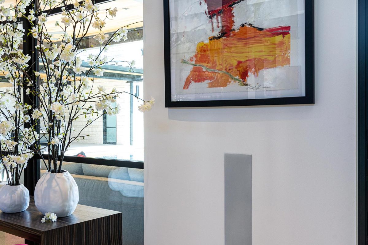 Abstract artwork hanging above a small wooden table with flowers