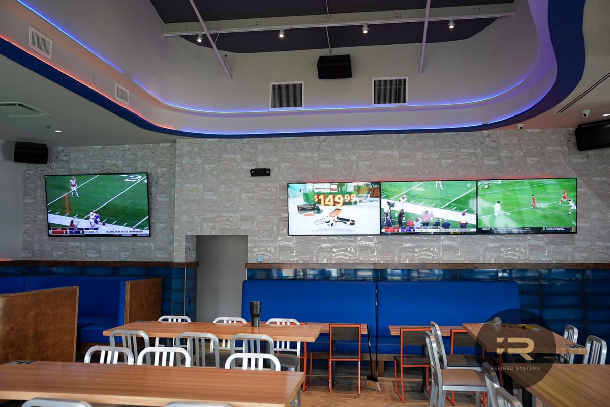 Multiple TVs playing sports in a modern bar with booths and high tables.