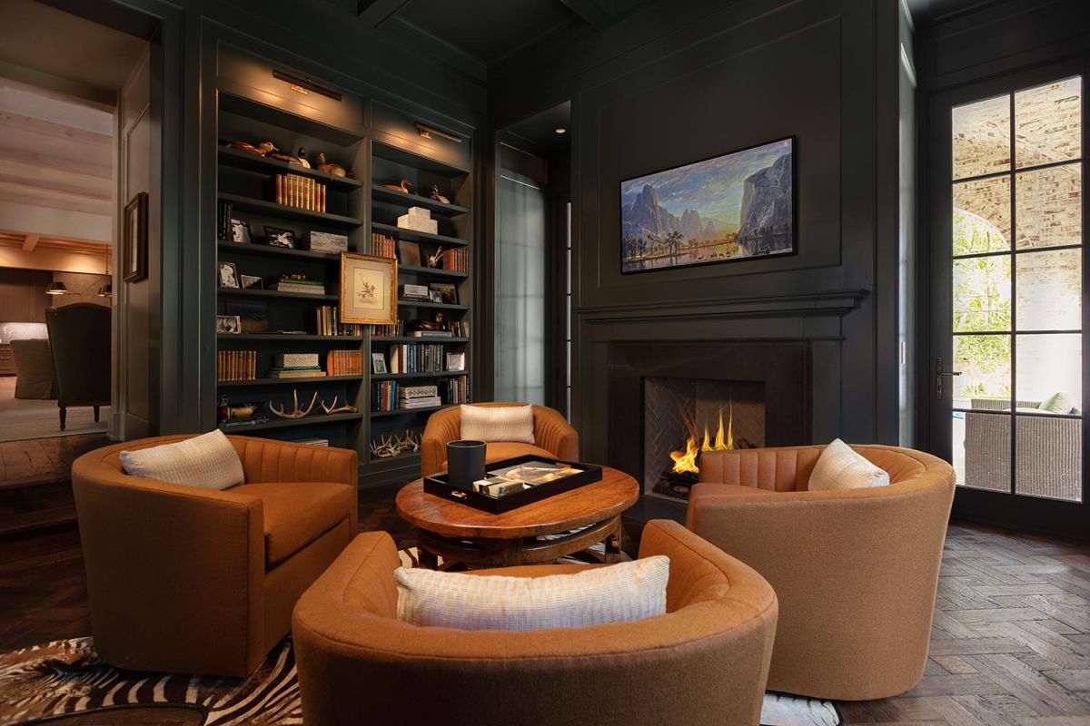 Elegant library with dark green walls, fireplace, and circular seating