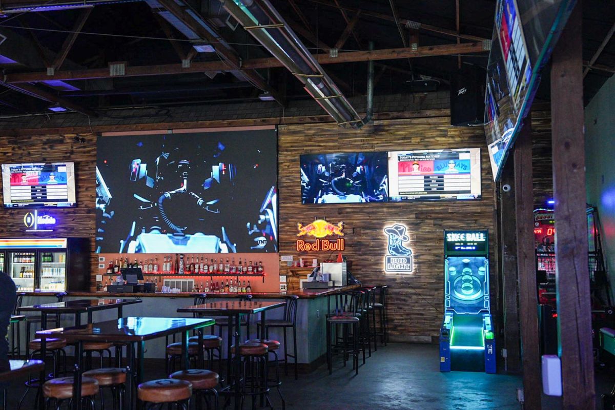 Bar area with neon signs, liquor shelves, and a large projection screen