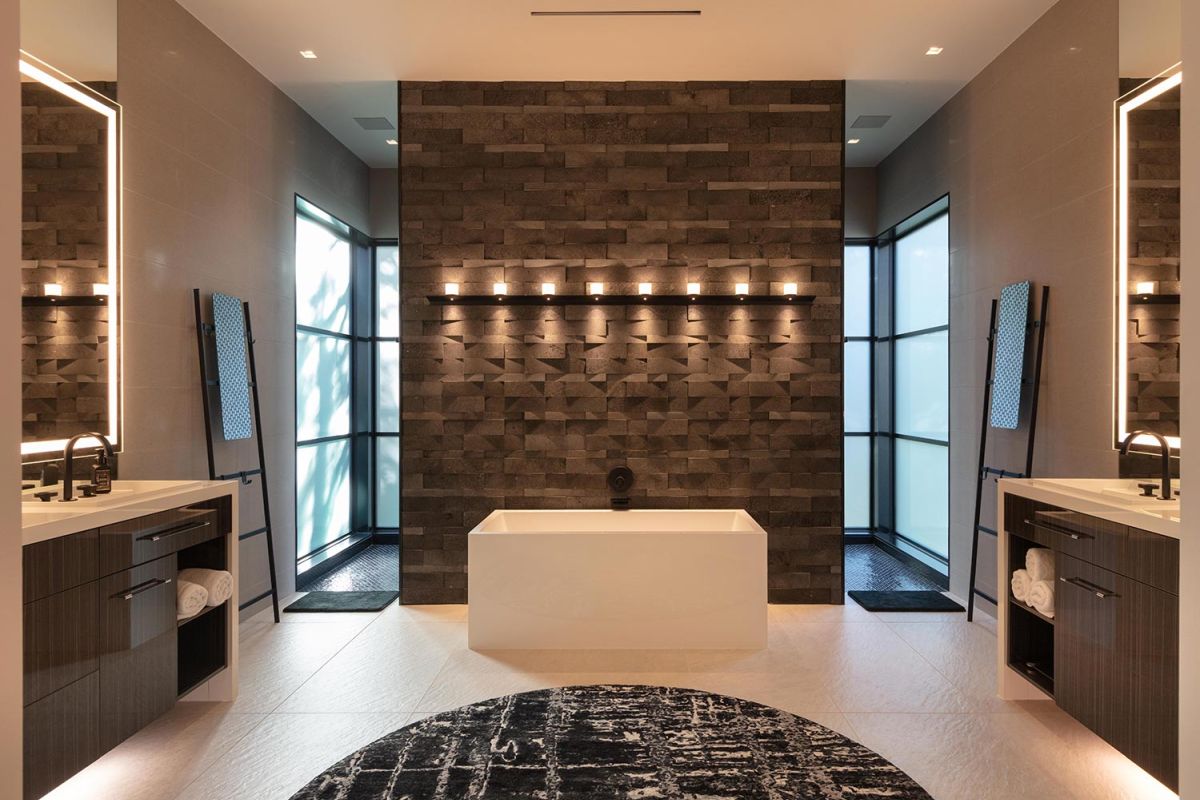 Bathroom with freestanding tub, black tile wall, and symmetrical sinks