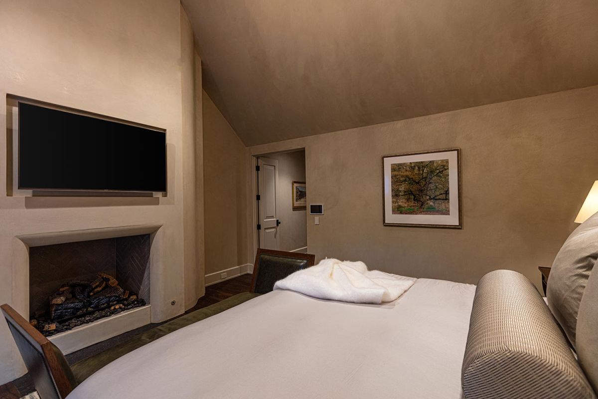 Bedroom with TV above fireplace and neutral-toned walls