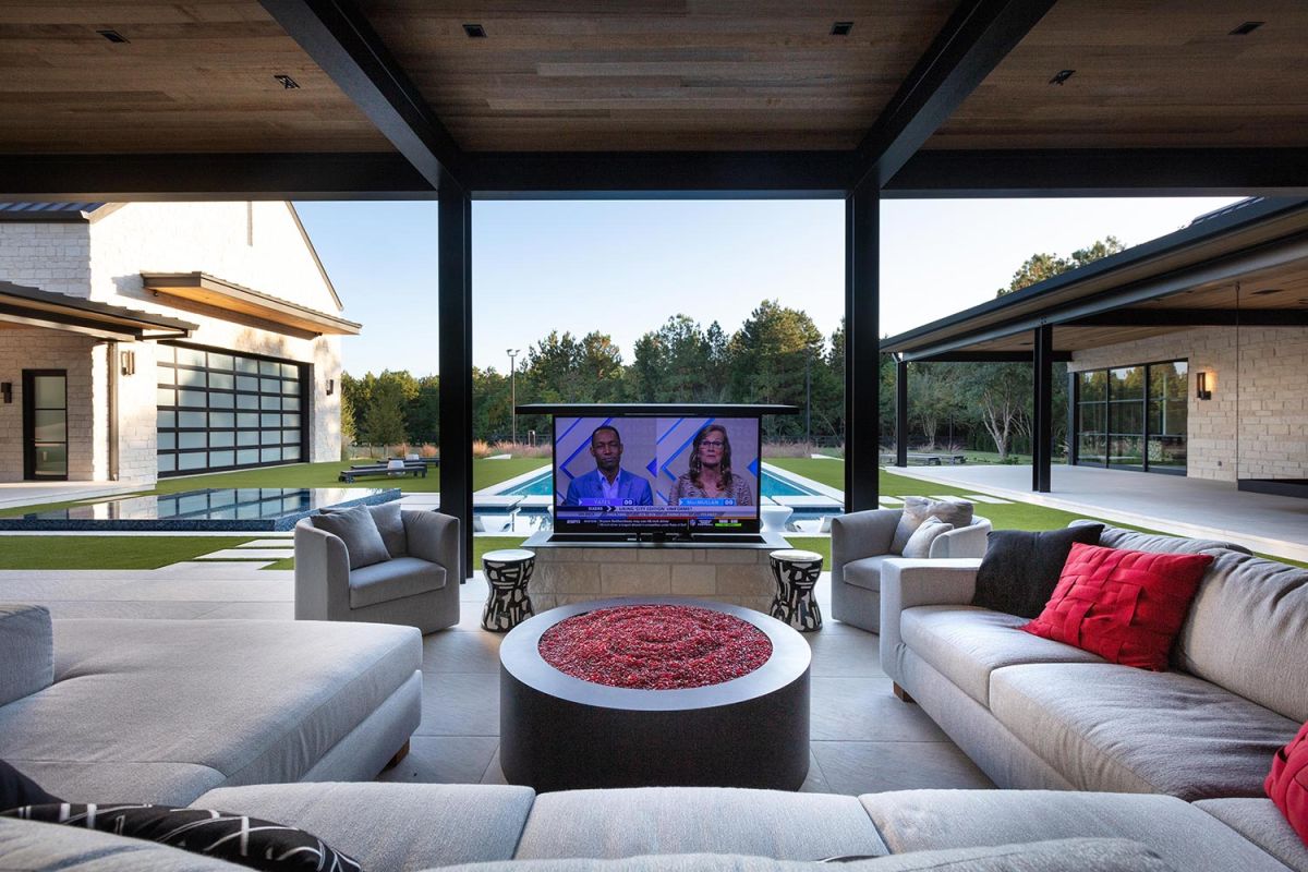 Outdoor lounge with retractable TV facing pool and lawn